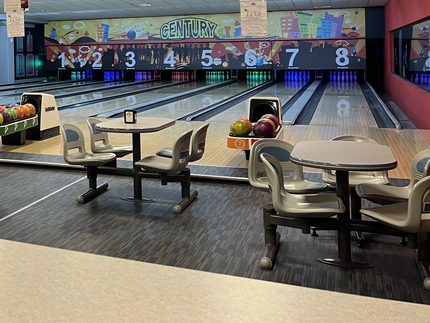 I tavolini del bowling davanti alle piste e al murale del Century